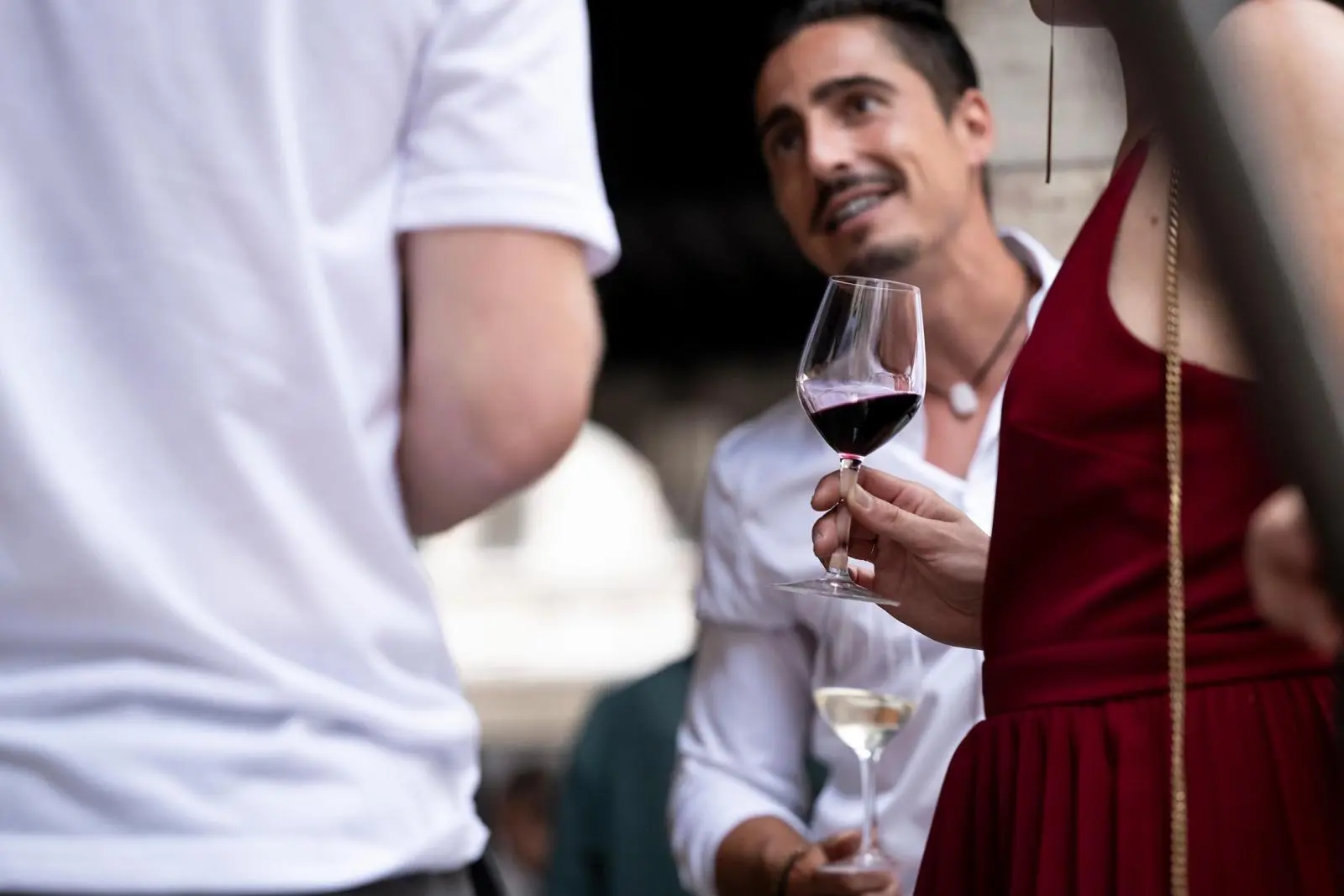 Photo d'une jeune femme buvant un verre de vin avec Damien Simone en fond
